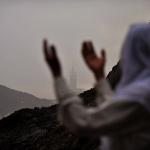 16.	Женщина читает молитвы на фоне Большой мечети. Огромное количество нелегальных паломников также участвуют в хадже каждый год.